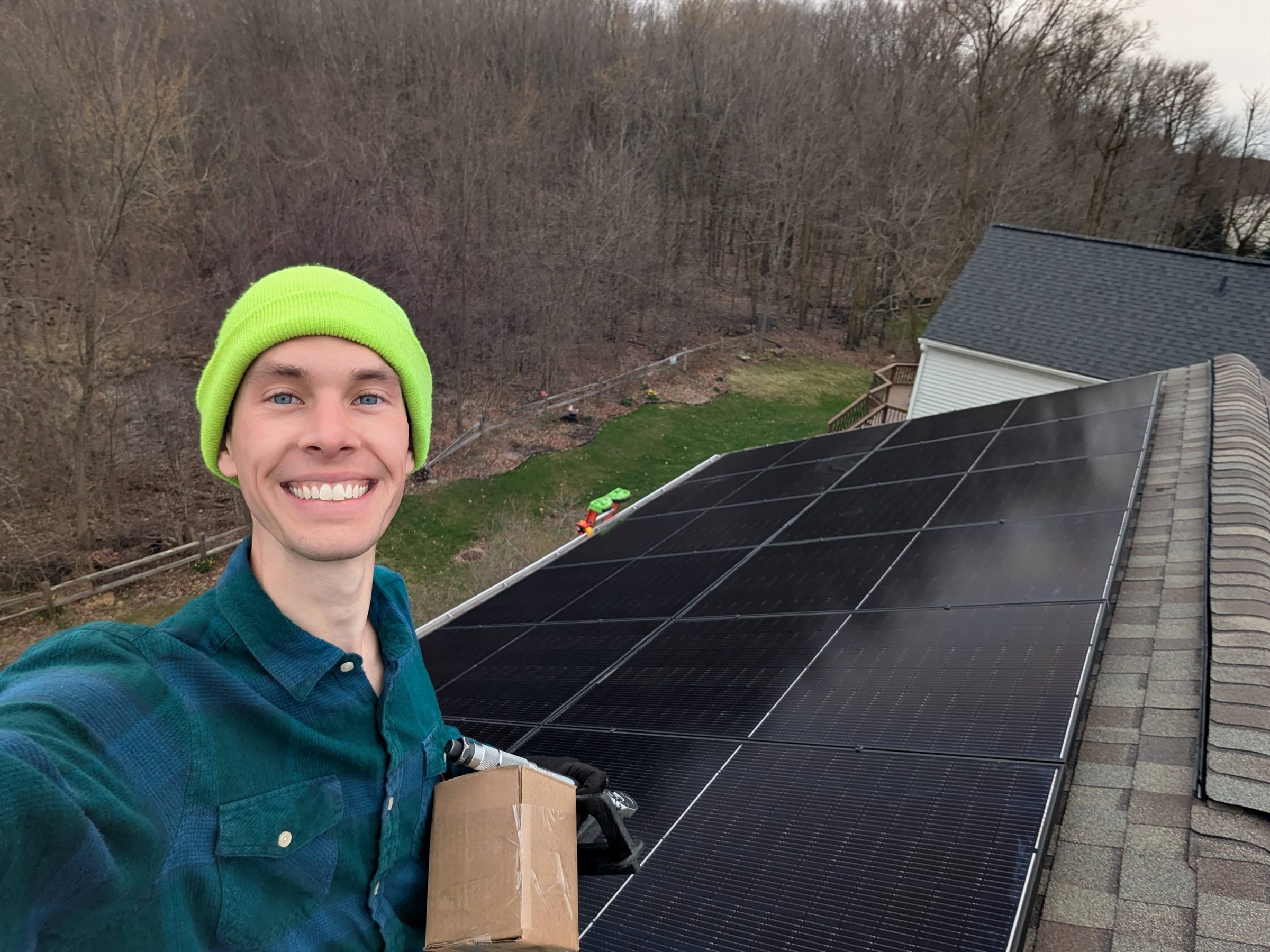 An Augustine Solar installer on a residential roof beside a completed run of solar modules
